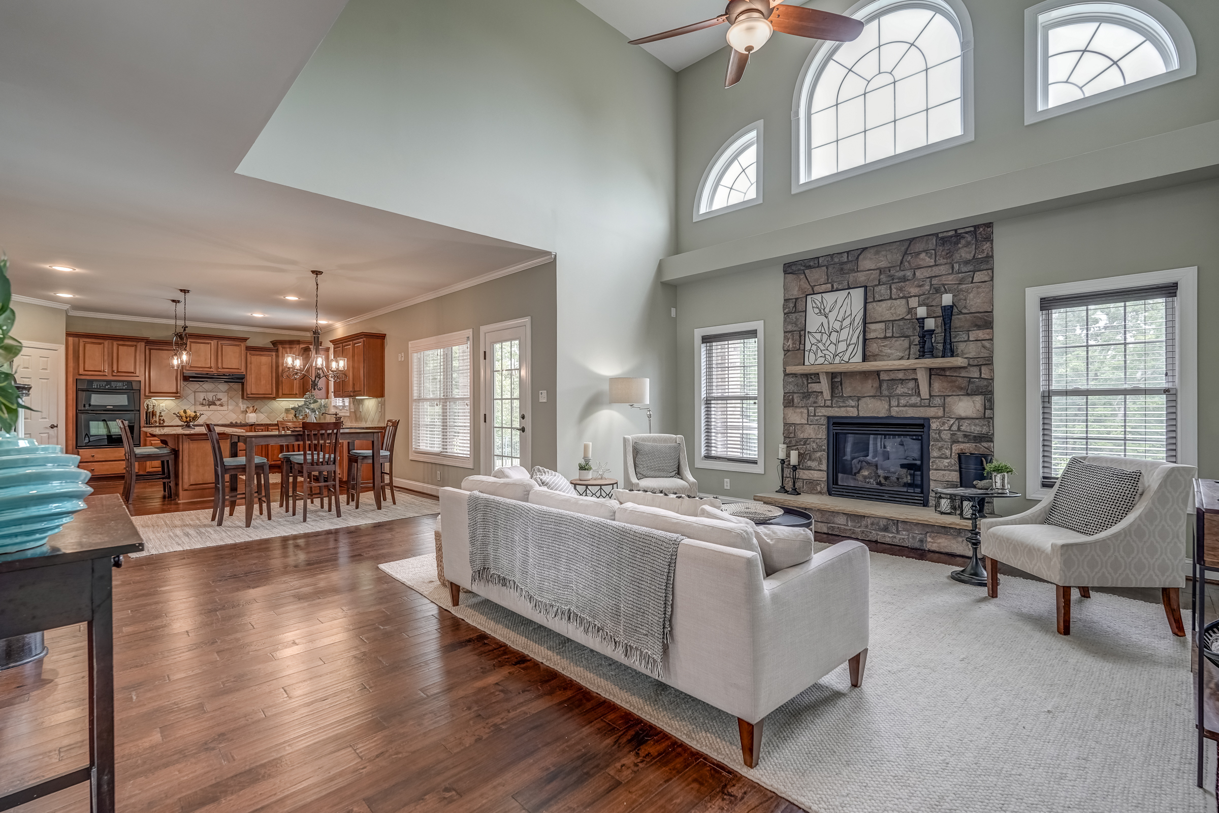 Spacious, open living area with soaring ceilings, stone fireplace, and eat-in gourmet kitchen